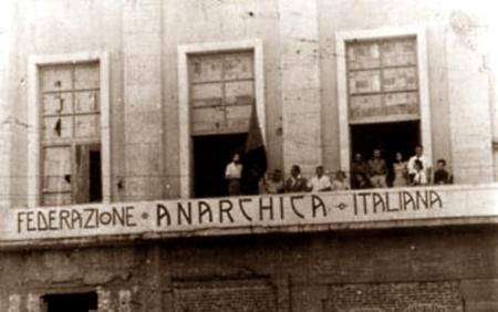 Casal de la FAI de Messina en los locales ocupados del Palazzo Littorio. Gino Cerrito es el primero por la izquierda, derecho, junto a la bandera (Messina, 28 de agosto de 1947)